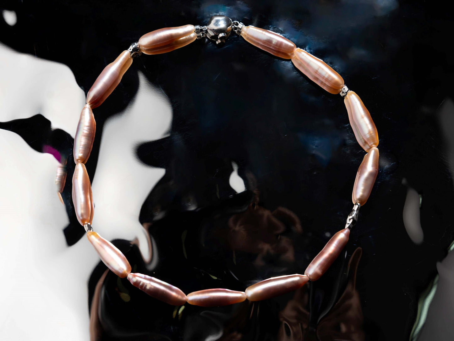 Pearl Necklace with pink beads on a reflective surface