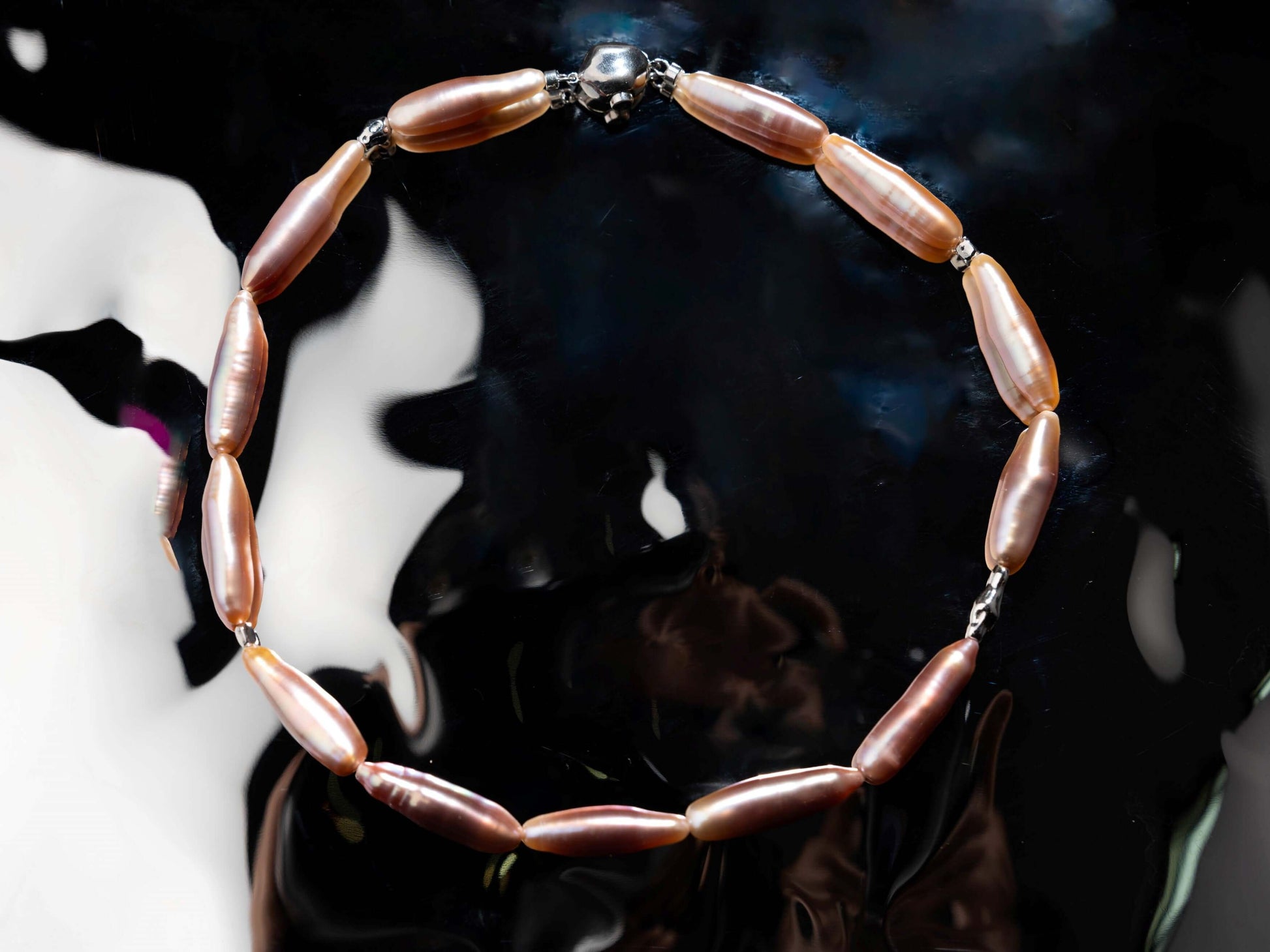 Pearl Necklace with pink beads on a reflective surface