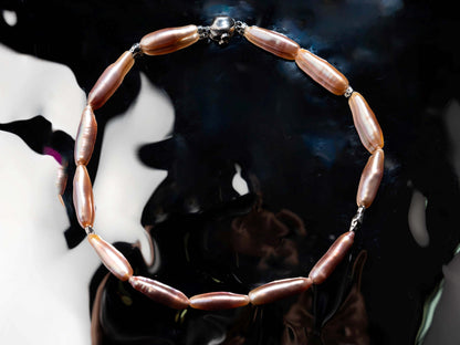 Pearl Necklace with pink beads on a reflective surface