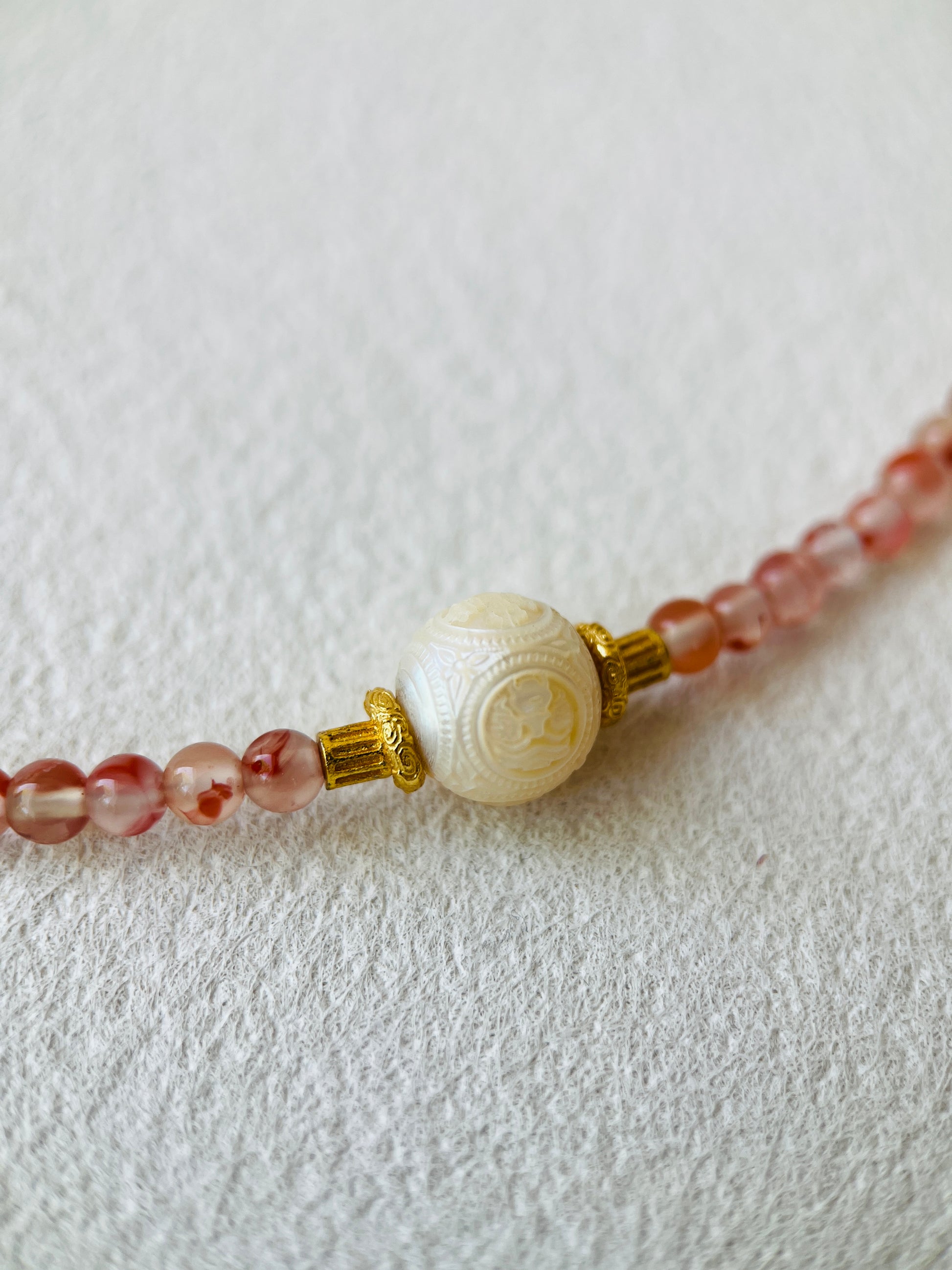Hand crafted white pearl on carnelian necklace on white background 
