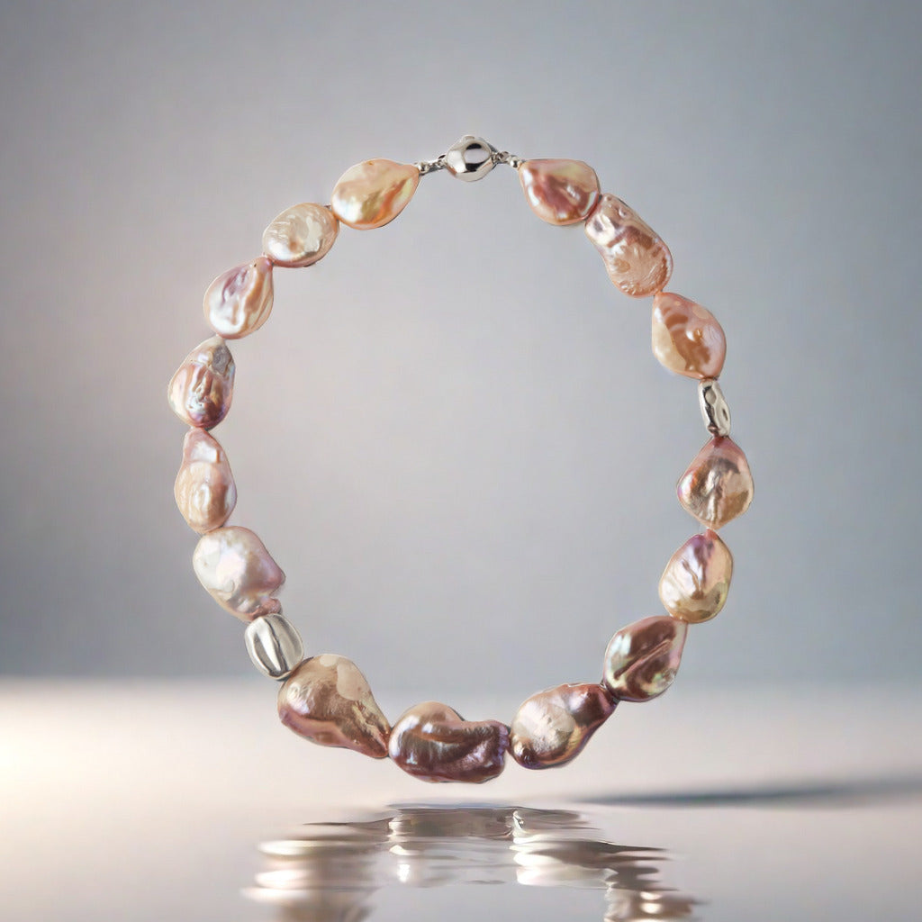 Pearl necklace with a silver clasp on a reflective surface with a gray background